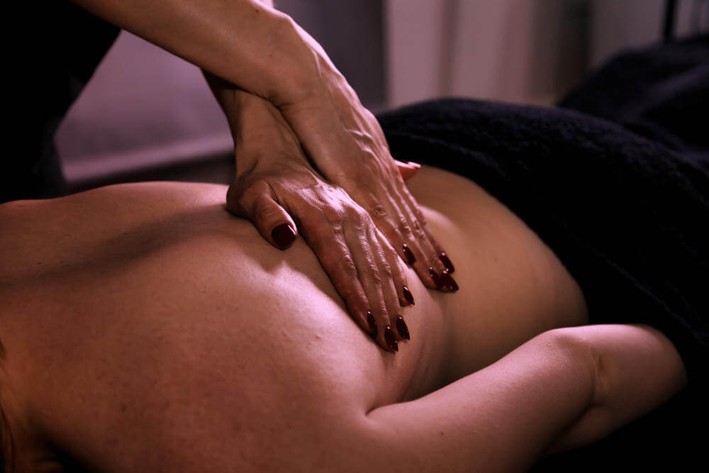 Inside a dim room, a skilled therapist is applying hands-on techniques to a person's back, promoting relaxation and therapeutic benefits through medical massage.